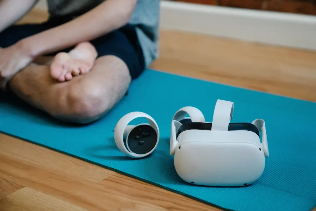 Homme assis sur un tapis de yoga avec un casque de réalité virtuelle posé à côté de lui, illustrant les applications de la VR dans le domaine de la santé et du bien-être