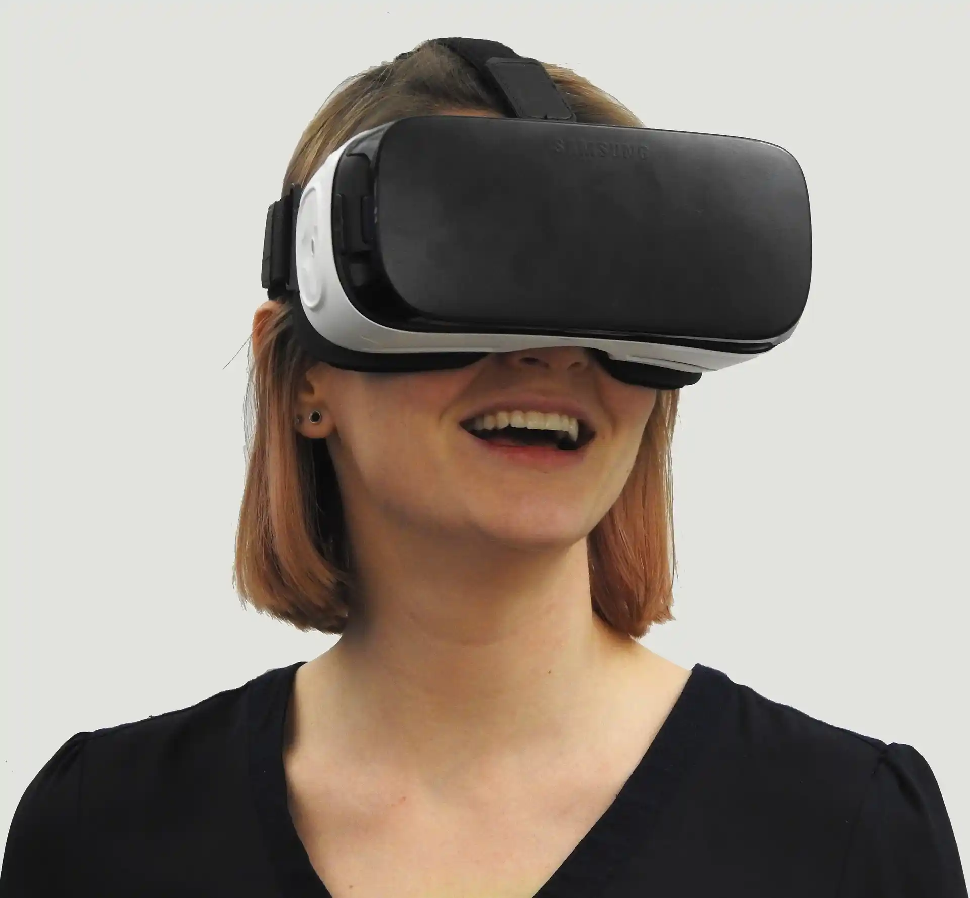 Femme souriante portant un casque VR pour découvrir un environnement immobilier en 360°