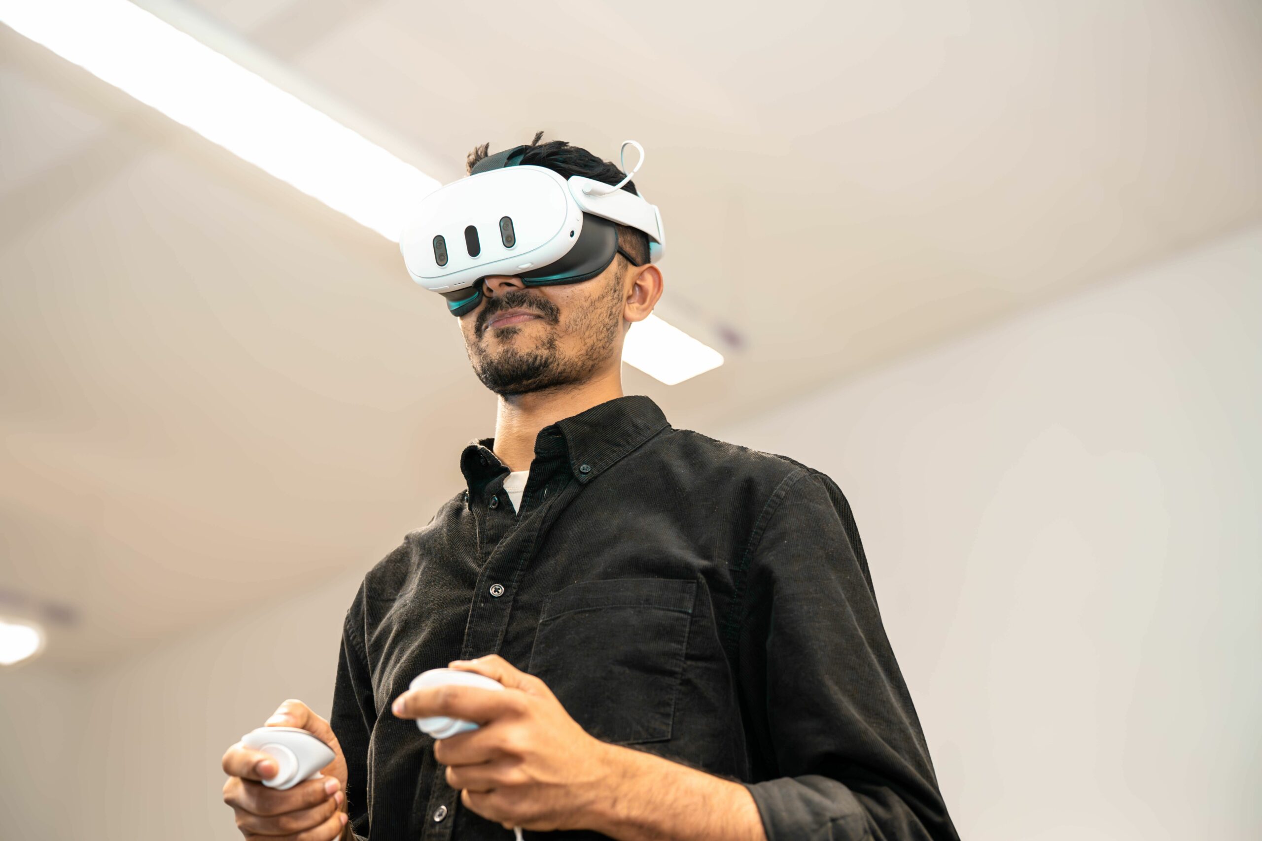 Personne équipée d’un casque de réalité virtuelle et de manettes pour profiter d’une expérience immersive.